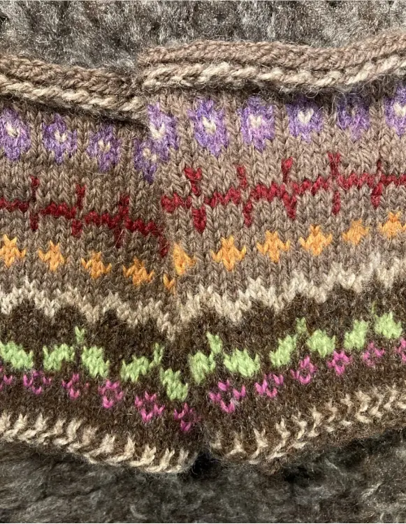 Färgstark stickning med tradition – textilglädje i varje maska Närbild på vackert mönstrad stickning i brunt med färgglada detaljer – traditionellt hantverk i Teija